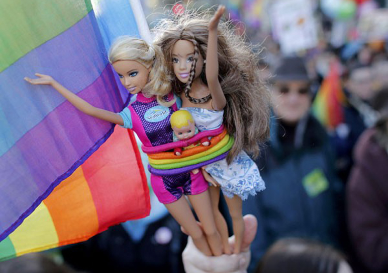 Manifestante segura bonecas Barbie em marcha pelas ruas de Paris