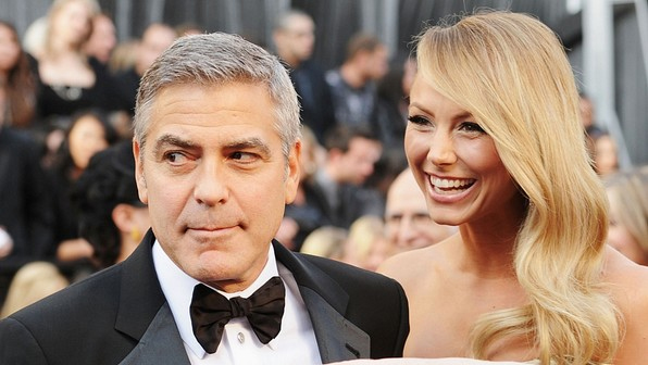 Ao lado da namorada Stacy Keibler, George Clooney brinca com fot�grafo no tapete vermelho do Oscar.